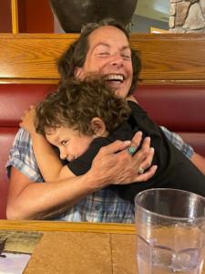 in a booth at a restaurant, Boo sits with her kid, smiling and laughing
