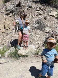 Boo outside with her kids; the kids are holding up rocks and sticks; Boo holds a white dog